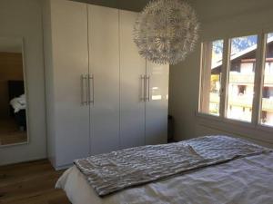a bedroom with white cabinets and a chandelier at Apartment Turmalin 2- Stock by Interhome in Lenk