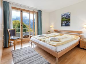 a bedroom with a large bed and a large window at Apartment Silberhorn Apt- V by Interhome in Wengen