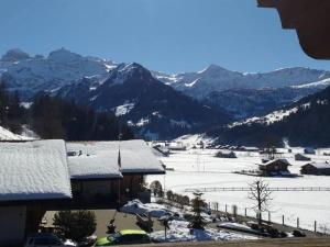 a snow covered village with mountains in the background at Apartment Bärnermutz # 2 by Interhome in Lenk
