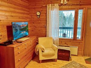 ein Wohnzimmer mit Fernseher, Sessel und Fenster in der Unterkunft Holiday Home Ruka-ihtinki 4 a 3 by Interhome in Niskala