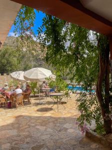 tifrit maison d'hôtes-Paradise valley في إيموزار دي عيدا و تنانه: مجموعة من الناس يجلسون على طاولات تحت مظلة