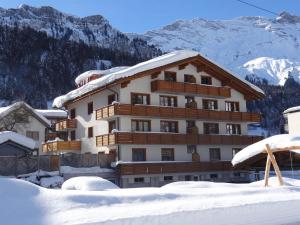 a building covered in snow with mountains in the background at Apartment Alpenstrasse 1 by Interhome in Engelberg