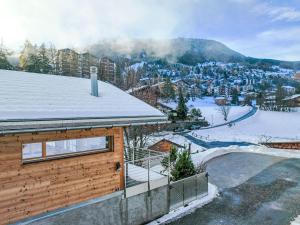 a house with a snow covered roof with a ski slope at Chalet Les penguins by Interhome in Nendaz