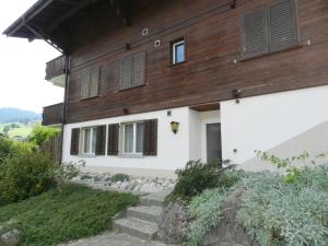 a white house with a wooden roof and stairs at Apartment Diamant by Interhome in Zweisimmen