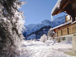 a snow covered path next to a building with mountains in the background at Apartment Am Schilf by Interhome in Lauenen