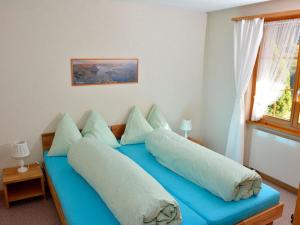 ein Schlafzimmer mit einem blauen Bett mit Kissen und einem Fenster in der Unterkunft Apartment Marielle by Interhome in Adelboden