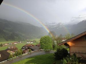 a rainbow over a village with a house and a road at Apartment Rottäli OG by Interhome in Lenk