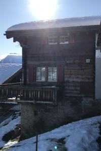 a log cabin in the snow with the sun behind it at Apartment Stubulti by Interhome in Mörel