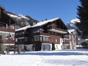 a large building in the snow with mountains in the background at Apartment Dorfstrasse 53a by Interhome in Engelberg