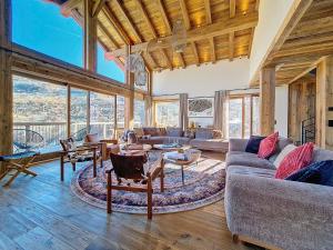 a living room with couches and tables and windows at Chalet La Panthère des Neiges in Saint-Martin-de-Belleville