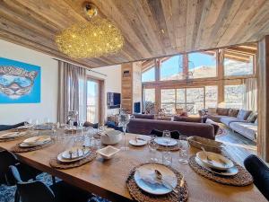 a dining room with a large wooden table with wine glasses at Chalet La Panthère des Neiges in Saint-Martin-de-Belleville
