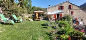 a yard with chairs and umbrellas and a house at La Fischaumière in Soleilhas
