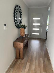 a hallway with a table and a mirror on the wall at Modern Four Bedroom Holiday Home Available in Deebing Heights in Loamside