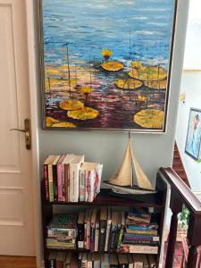 a painting hanging above a book shelf with books at MAR VERDE - Parede-Cascais in Parede
