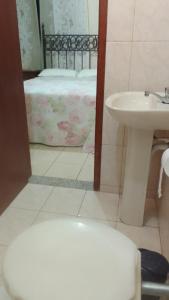 a bathroom with a sink and a bed and a mirror at Hospedaria meu Lar in Rio das Ostras