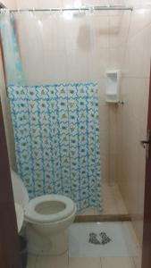 a bathroom with a toilet and a shower curtain at Hospedaria meu Lar in Rio das Ostras