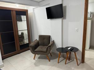 een woonkamer met een stoel en een tafel bij Apartamento Setor Universitário in Goiânia