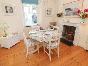 een eetkamer met een tafel en stoelen en een open haard bij April Cottage in Falmouth