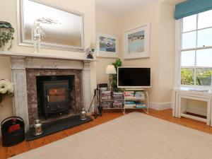 een woonkamer met een open haard en een televisie bij April Cottage in Falmouth