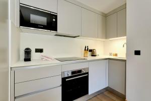 eine Küche mit weißen Schränken und einem schwarzen Gerät in der Unterkunft Discover this new apartment with your family in Saint-Bon-Tarentaise