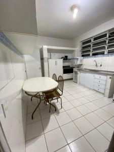 a white kitchen with a table and two chairs at Santorini House in Guarujá