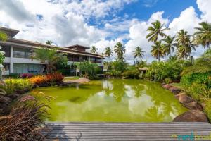 a pond in front of a building with palm trees at Ykutiba Imbassaí - Apartamento Superior - I103 in Imbassai