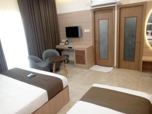 a hotel room with two beds and a desk and a television at Grand Silver in Chennai
