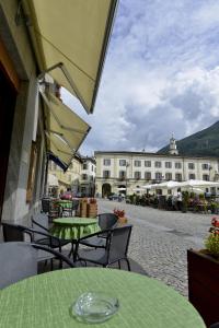 eine Außenterrasse mit Tischen und Stühlen sowie ein Gebäude in der Unterkunft Albergo Gusmeroli in Tirano