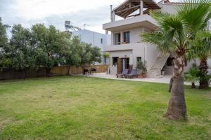 a white house with a palm tree in the yard at Natalia's Apartment in Tavronitis in Tavronitis