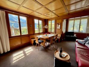 a living room with a table and chairs and windows at Apartment Haldematt by Interhome in Adelboden