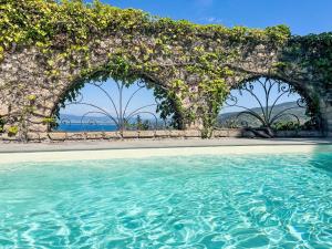 an outdoor swimming pool with a stone wall and water at Holiday Home Sole by Interhome in Porto Santo Stefano