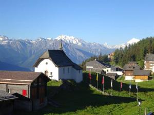 a small church on a hill with mountains in the background at Apartment Robert EG Süd by Interhome in Bettmeralp
