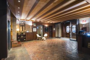 a lobby with wooden ceilings and a room with chairs at Hotel Alda Castillo de Olite in Olite