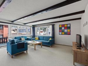 a living room with blue couches and a tv at Apartment Seeli by Interhome in Churwalden