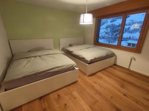 two beds in a room with a window at Apartment Lenk Unique by Interhome in Lenk