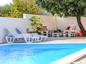a pool with chairs and a table and a tree at Holiday Home Karlo by Interhome in Posedarje