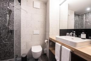 a bathroom with a sink and a toilet and a shower at Hotel Krone - Aktiv & Erholt in Churwalden
