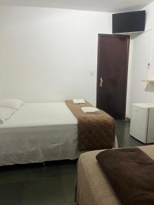 a hotel room with two beds and a cabinet at Pousada e Restaurante Dona Lu in Itaperuna