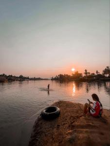 a woman sitting on the edge of a body of water at souksanh River Bungalow in Along +1 photo
