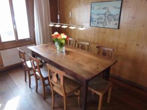 a wooden table with chairs and a vase of flowers on it at Apartment Hälmehois by Interhome in Engelberg