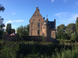 an old brick building with a tower in a field at B&B La demeure du Papillon in Mouscron