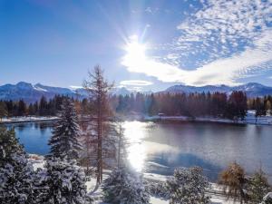 vistas a un lago con árboles nevados y montañas en Studio Golf Bellerive 76 by Interhome, en Crans-Montana