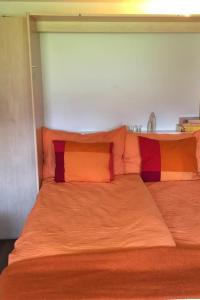 Una cama con dos almohadas de colores encima. en Apartment Cresta di Saas by Interhome, en Saas-Grund