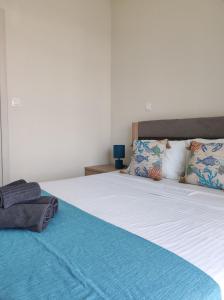 a bedroom with a large bed with blue sheets and pillows at Sea Breeze 101 in Neoi Epivates