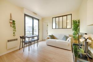 a living room with a white couch and a table at Le Molière des Bords de Seine - 15 min de Paris in Asnières-sur-Seine