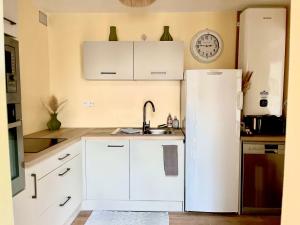 Una cocina con gabinetes blancos y un refrigerador. en F3 confort proche Château-CDG-Paris, en Écouen