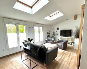 Una sala de estar con tragaluces y un sofá y una mesa. en F3 confort proche Château-CDG-Paris, en Écouen