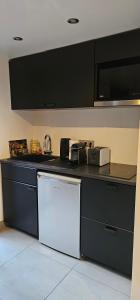 een keuken met een zwart aanrecht met een wastafel bij Maison Les Vallées in La Garenne-Colombes