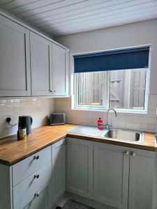 a kitchen with white cabinets and a sink and a window at Lights of Broadway Gaeltacht Quarter in Belfast