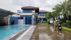 a person standing next to a swimming pool in front of a building at Villa Homestay Thanh Hiền in Ho Tram